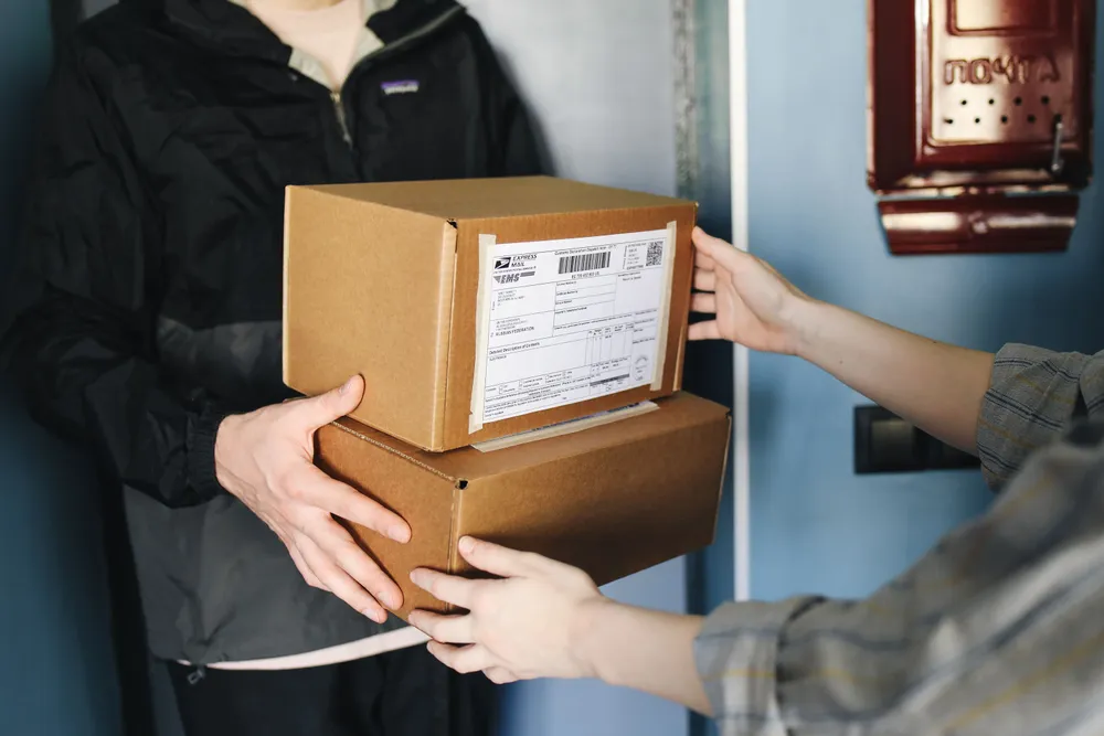 A courier handing labelled parcels to a recipient at the door